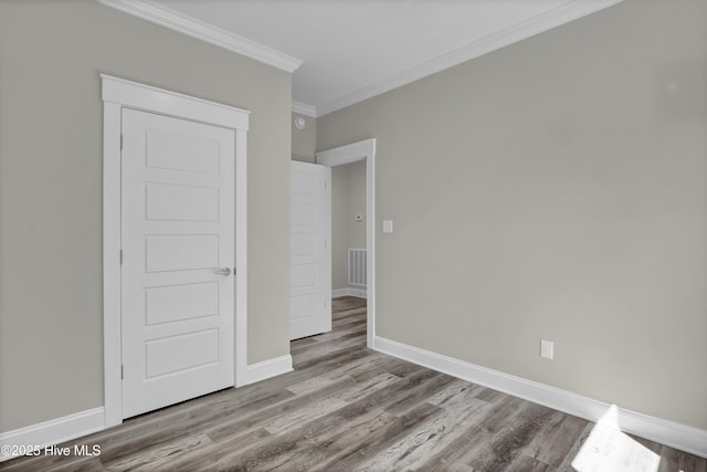 101 SE 68th St, Oak Island, NC 28465 - unfurnished bedroom featuring visible vents, baseboards, crown molding, and wood finished floors