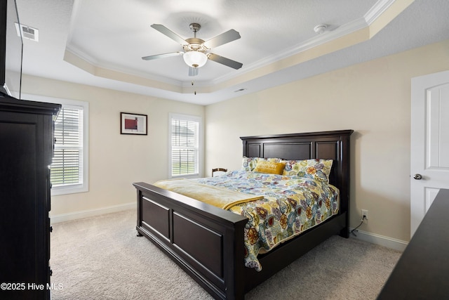 bedroom featuring a raised ceiling, light colored carpet, baseboards, and multiple windows