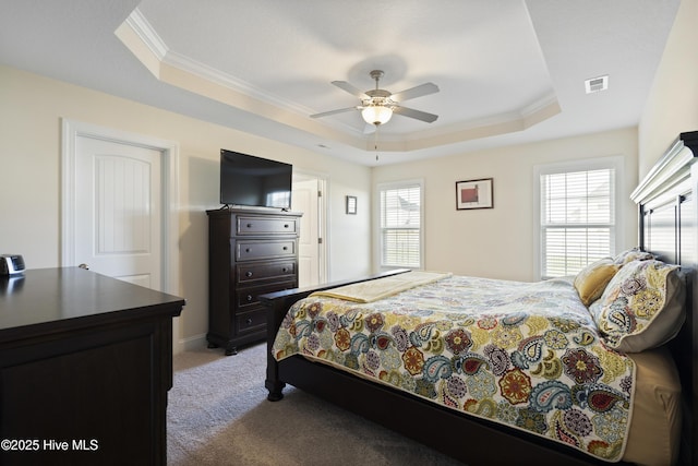 bedroom featuring crown molding, visible vents, a tray ceiling, ceiling fan, and light colored carpet