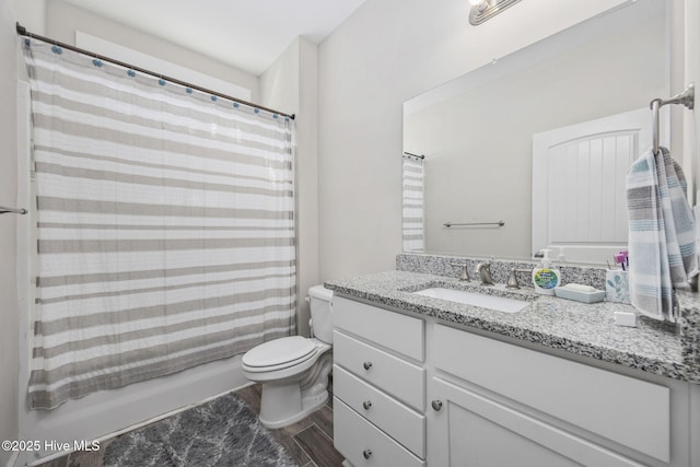 bathroom with vanity, toilet, wood finished floors, and shower / tub combo