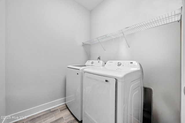 laundry room featuring laundry area, light wood-style flooring, baseboards, and separate washer and dryer