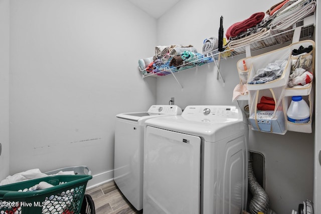 clothes washing area with laundry area, baseboards, separate washer and dryer, and light wood-type flooring