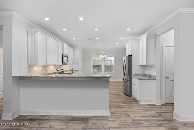 kitchen featuring white cabinetry, light stone countertops, appliances with stainless steel finishes, and a peninsula