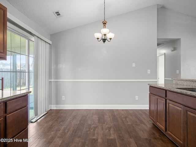 unfurnished dining area featuring visible vents, dark wood-style flooring, baseboards, a notable chandelier, and vaulted ceiling