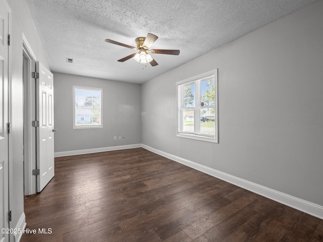 unfurnished bedroom featuring baseboards, a textured ceiling, wood finished floors, and multiple windows
