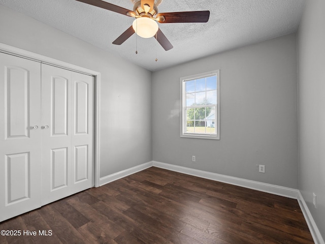 unfurnished bedroom featuring a closet, dark wood-style flooring, baseboards, a textured ceiling, and a ceiling fan