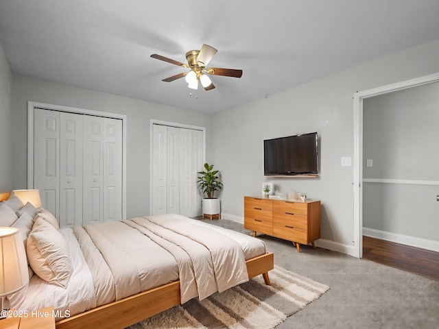 bedroom with light colored carpet, baseboards, multiple closets, and a ceiling fan