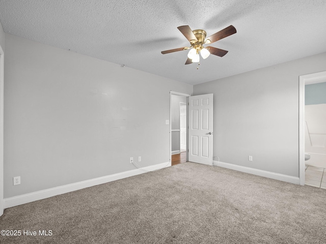unfurnished bedroom with baseboards, carpet flooring, ensuite bath, and a textured ceiling