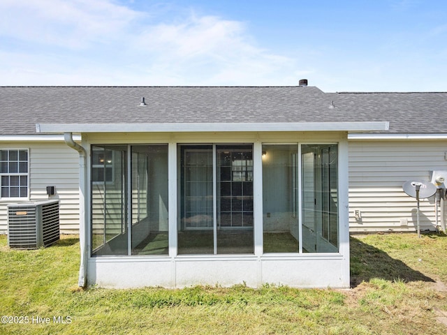 back of property with roof with shingles, central AC unit, and a sunroom