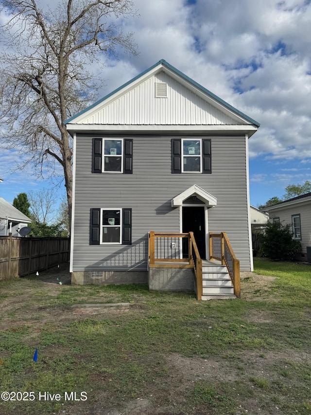 back of property featuring a yard, fence, and board and batten siding