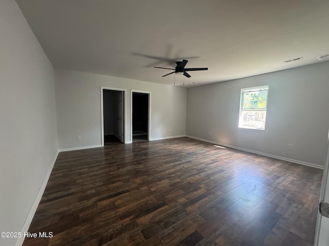 empty room with baseboards, visible vents, dark wood-style flooring, and a ceiling fan