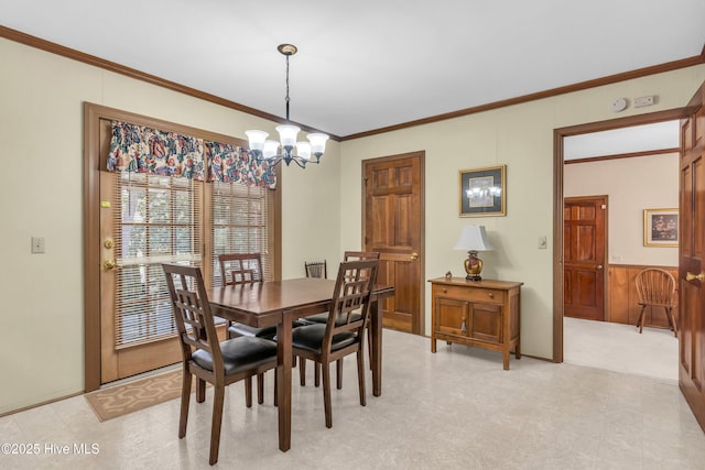 dining room with a chandelier, wainscoting, and ornamental molding