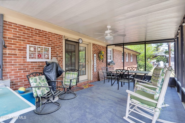 sunroom featuring outdoor dining space, a wood stove, and a ceiling fan