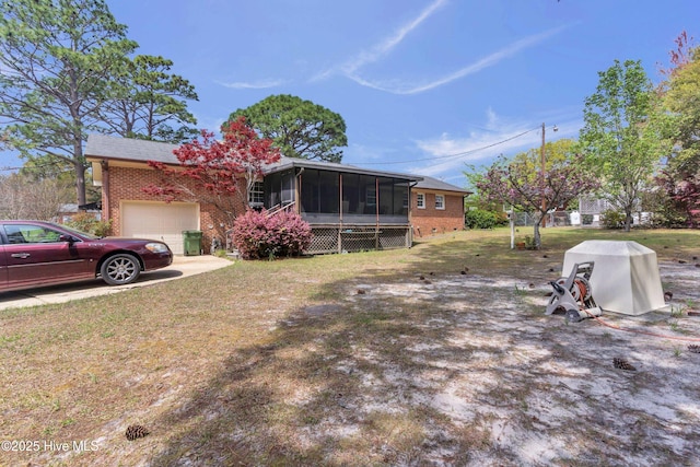 view of front of house featuring brick siding, a front lawn, a sunroom, and a garage