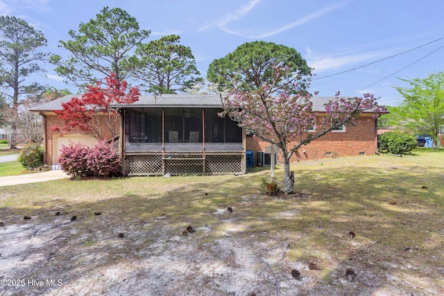 view of front of home with a front yard, a sunroom, crawl space, concrete driveway, and brick siding
