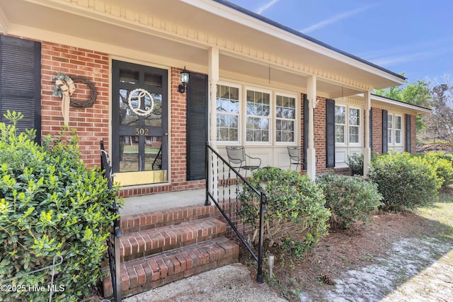 property entrance featuring a porch and brick siding