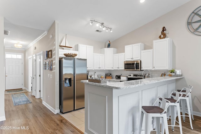5006 Carleton Dr Unit 90, Wilmington, NC 28403 - kitchen with appliances with stainless steel finishes, a peninsula, white cabinetry, backsplash, and ornamental molding