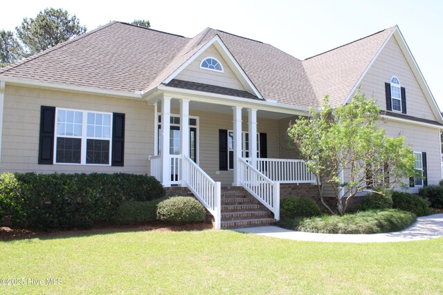 view of front of house with covered porch, a front lawn, and roof with shingles