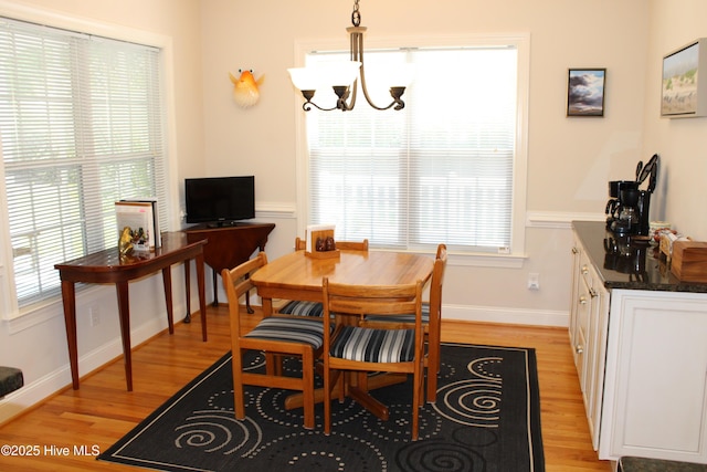 dining area featuring light wood-style flooring, baseboards, and a chandelier