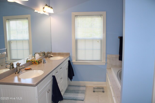 bathroom featuring baseboards, a sink, and tiled tub