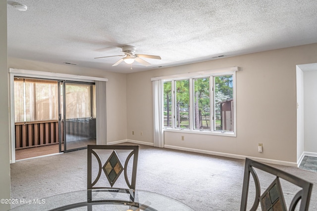 carpeted empty room with baseboards, visible vents, a textured ceiling, and a ceiling fan