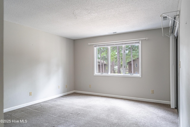 carpeted spare room with a textured ceiling, baseboards, and visible vents