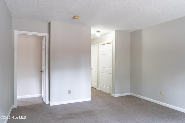carpeted spare room featuring a textured ceiling and baseboards