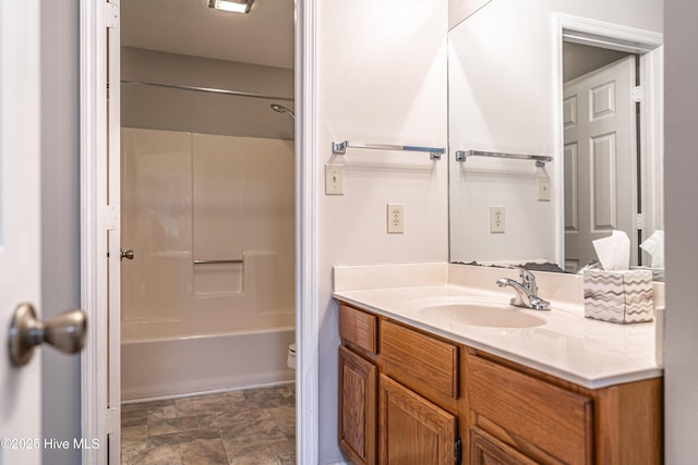 full bathroom featuring stone finish flooring, vanity, and bathtub / shower combination