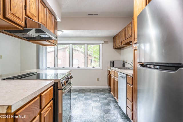 kitchen with brown cabinetry, appliances with stainless steel finishes, visible vents, and under cabinet range hood