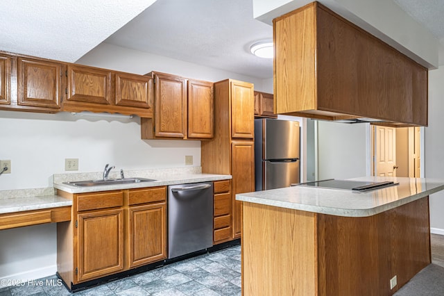 kitchen featuring a textured ceiling, appliances with stainless steel finishes, light countertops, a sink, and brown cabinets
