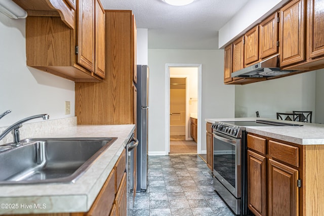 kitchen featuring a sink, light countertops, appliances with stainless steel finishes, under cabinet range hood, and brown cabinets