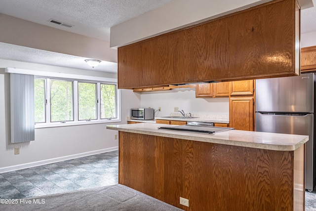 kitchen featuring a textured ceiling, visible vents, appliances with stainless steel finishes, a sink, and light countertops