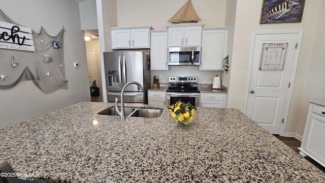 1905 Coleman Lake Dr, Calabash, NC 28467 - kitchen featuring appliances with stainless steel finishes, a sink, white cabinets, light stone countertops, and a center island with sink