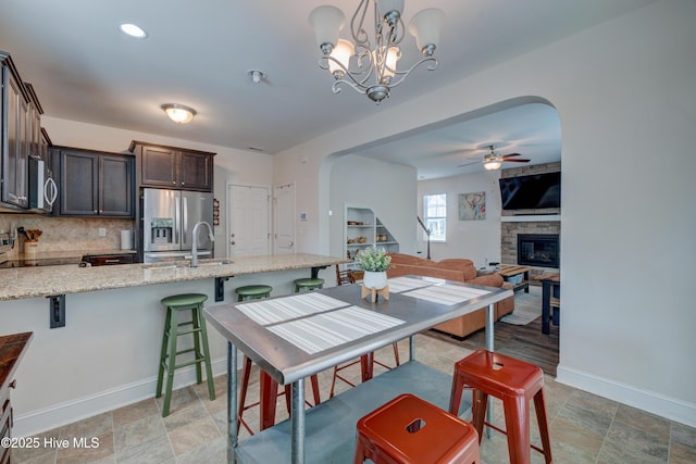 8603 Lanvale Forest Dr, Leland, NC 28451 - kitchen with arched walkways, appliances with stainless steel finishes, dark brown cabinetry, baseboards, and ceiling fan