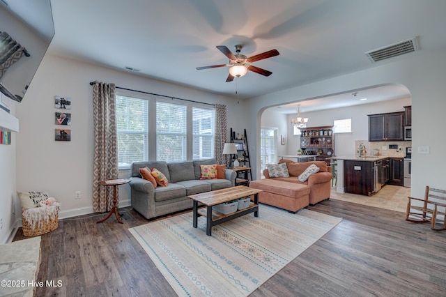 8603 Lanvale Forest Dr, Leland, NC 28451 - living area with arched walkways, ceiling fan, light wood finished floors, a chandelier, and baseboards