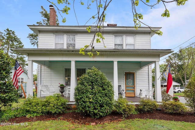 view of front of house featuring a chimney and covered porch