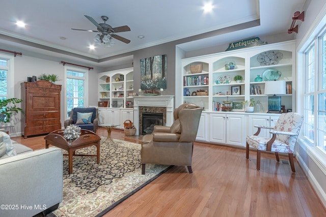 living room with healthy amount of natural light, light wood-type flooring, and ornamental molding