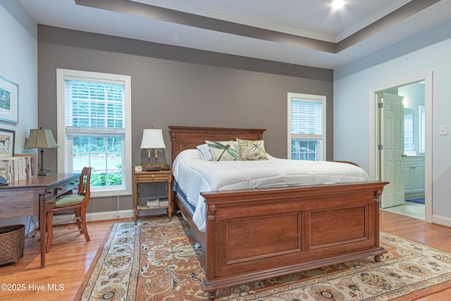 bedroom with light wood finished floors, crown molding, multiple windows, baseboards, and ensuite bathroom