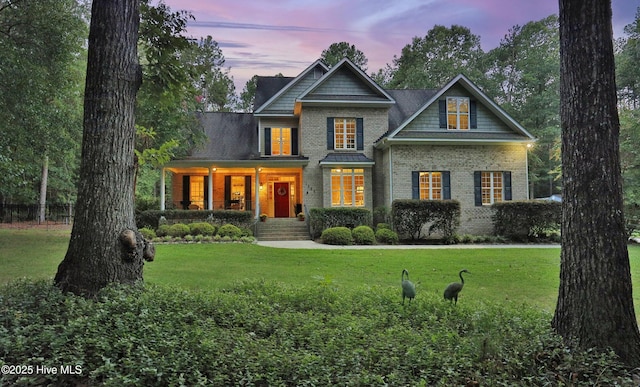 view of front of home with a porch, a front lawn, and brick siding