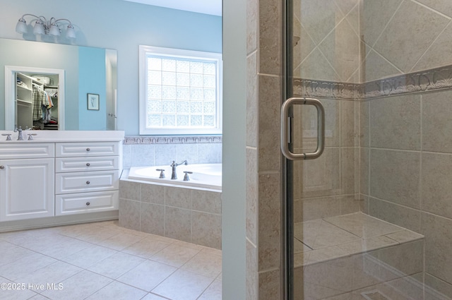 bathroom featuring a stall shower, a walk in closet, a bath, tile patterned flooring, and vanity