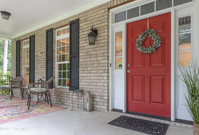 entrance to property with a porch and brick siding