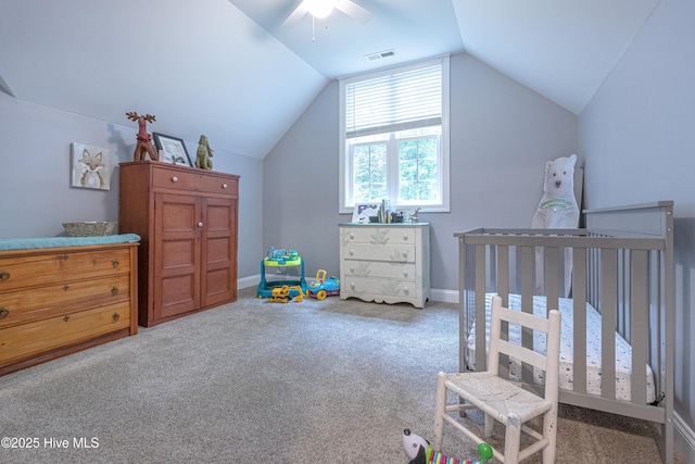 carpeted bedroom with lofted ceiling, baseboards, a crib, and ceiling fan