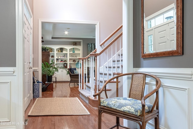 foyer with stairway, wood finished floors, a wainscoted wall, and a decorative wall