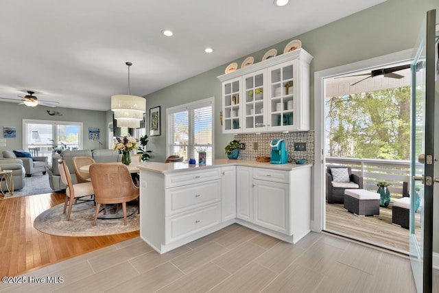 334 NE 48th St, Oak Island, NC 28465 - kitchen with ceiling fan, a peninsula, recessed lighting, light countertops, and glass insert cabinets