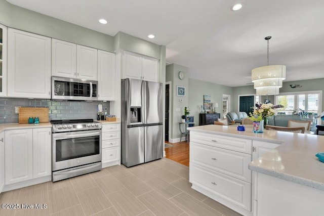 334 NE 48th St, Oak Island, NC 28465 - kitchen featuring stainless steel appliances, white cabinets, backsplash, open floor plan, and recessed lighting