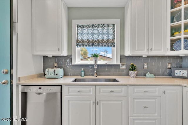 334 NE 48th St, Oak Island, NC 28465 - kitchen featuring dishwasher, a sink, white cabinets, backsplash, and glass insert cabinets
