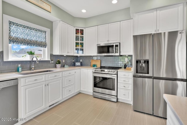 334 NE 48th St, Oak Island, NC 28465 - kitchen with appliances with stainless steel finishes, a sink, light countertops, white cabinetry, and tasteful backsplash