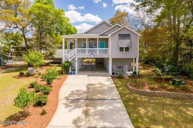 334 NE 48th St, Oak Island, NC 28465 - raised beach house with a ceiling fan, a carport, a porch, and concrete driveway