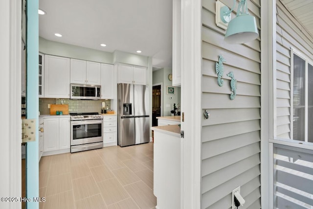 334 NE 48th St, Oak Island, NC 28465 - kitchen with appliances with stainless steel finishes, light countertops, white cabinets, decorative backsplash, and recessed lighting