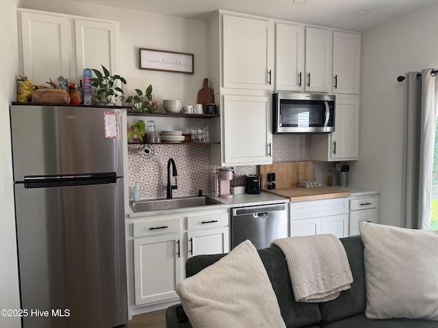 334 NE 48th St, Oak Island, NC 28465 - kitchen featuring stainless steel appliances, a sink, backsplash, light countertops, and white cabinetry
